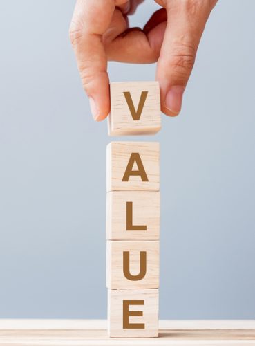 Business man hand holding wooden cube block with Value business word on table background. Mission, Vision and core values concept
